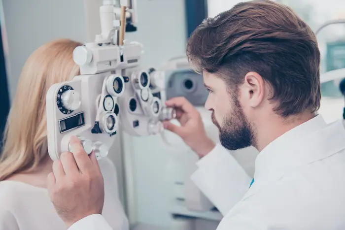Why Comprehensive Eye Exams Detect More Than Just Vision Changes 6 Comprehensive Eye Exams – Optometrist Conducting A Vision Test With A Phoropter On A Patient.