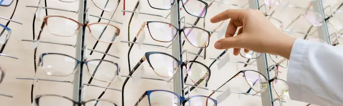 Top Eyeglass Frame Styles For Active Seniors In The Villages 5 Eyeglass Frames Selection On Display With A Hand Choosing Stylish Glasses
